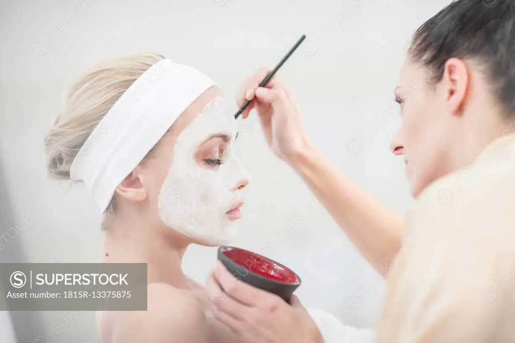 Young woman in spa receiving facial mask