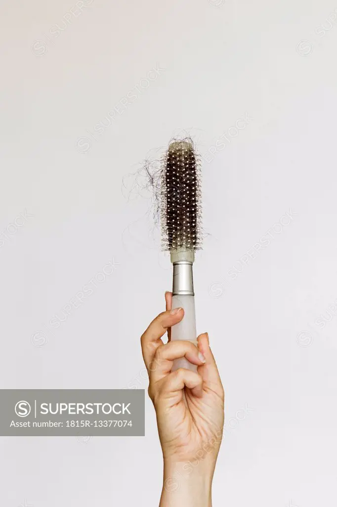Hand holds a brush full of lost hair
