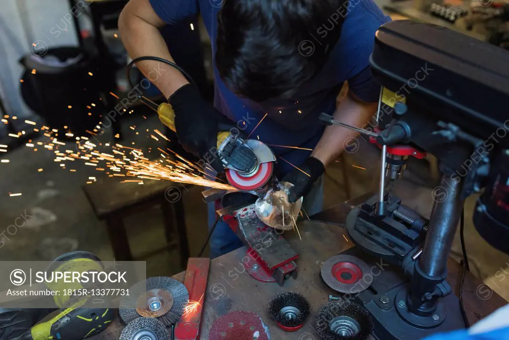Forger grinding metal in workshop