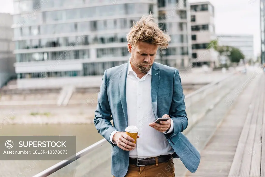 Businessman with cell phone and coffee to go on bridge