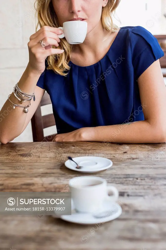 Woman drinking espresso in a sidewalk cafe, partial view
