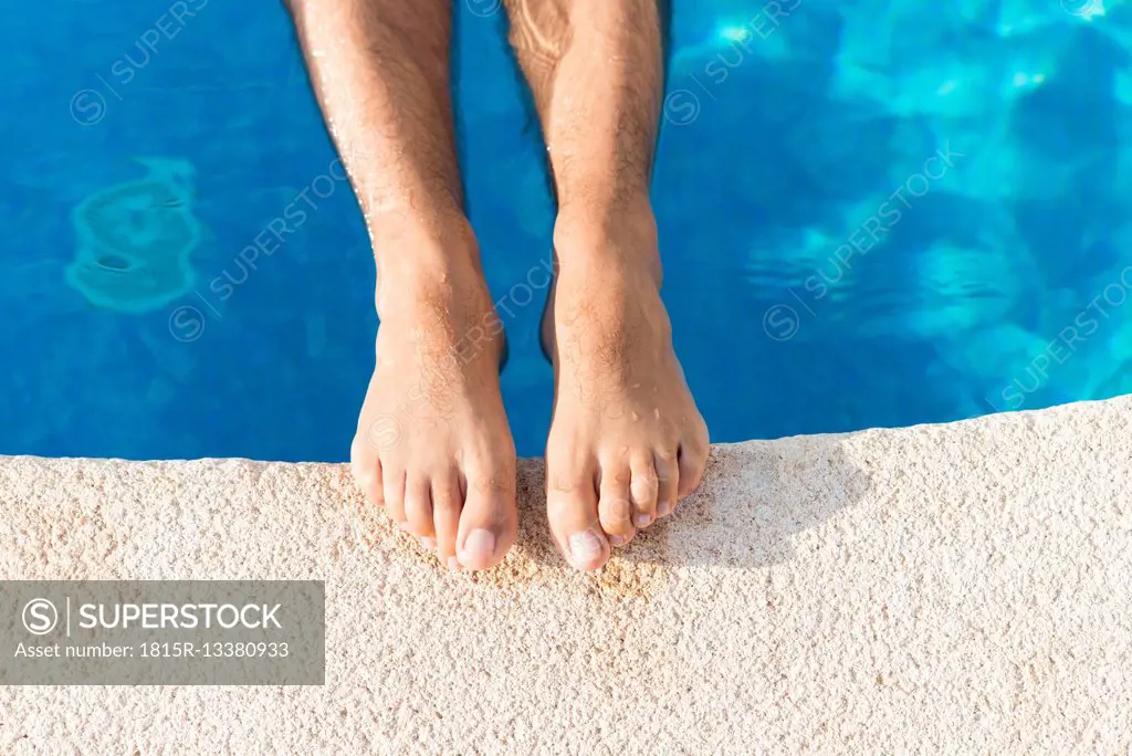 Bare feet of man on edge of swimming pool