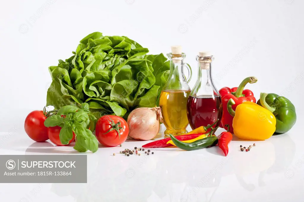 Lettuce with vinegar, olive oil, pepperonis, tomatoes and peppercorns on white background, close up