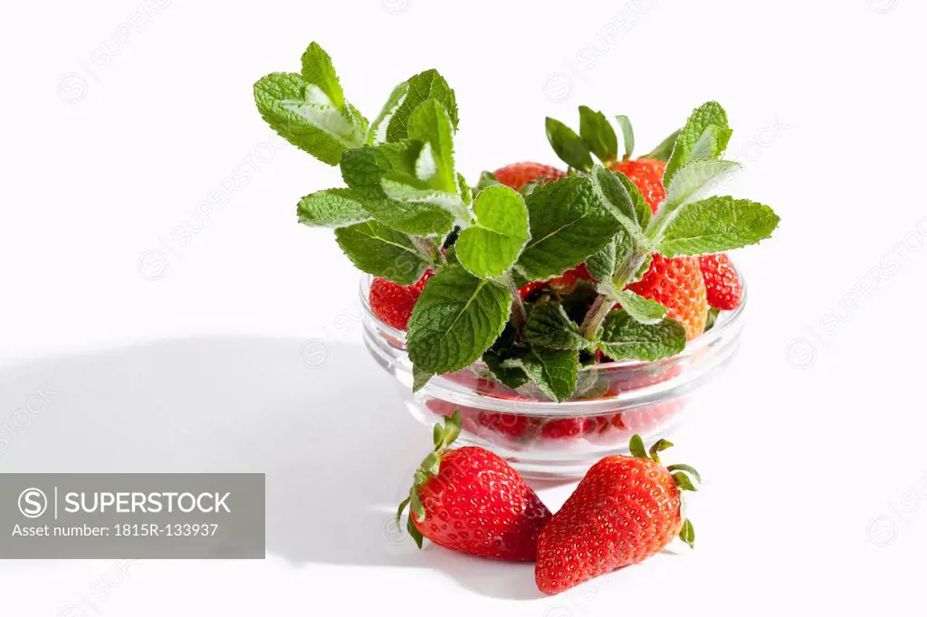 Bowl of strawberries with mint on white background, close up