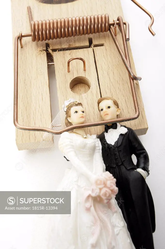 Wedding couple figurines lying in mouse trap, close-up