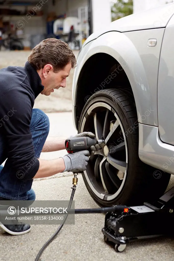 Germany, Bavaria, Kaufbeuren, Mature man changing car tire