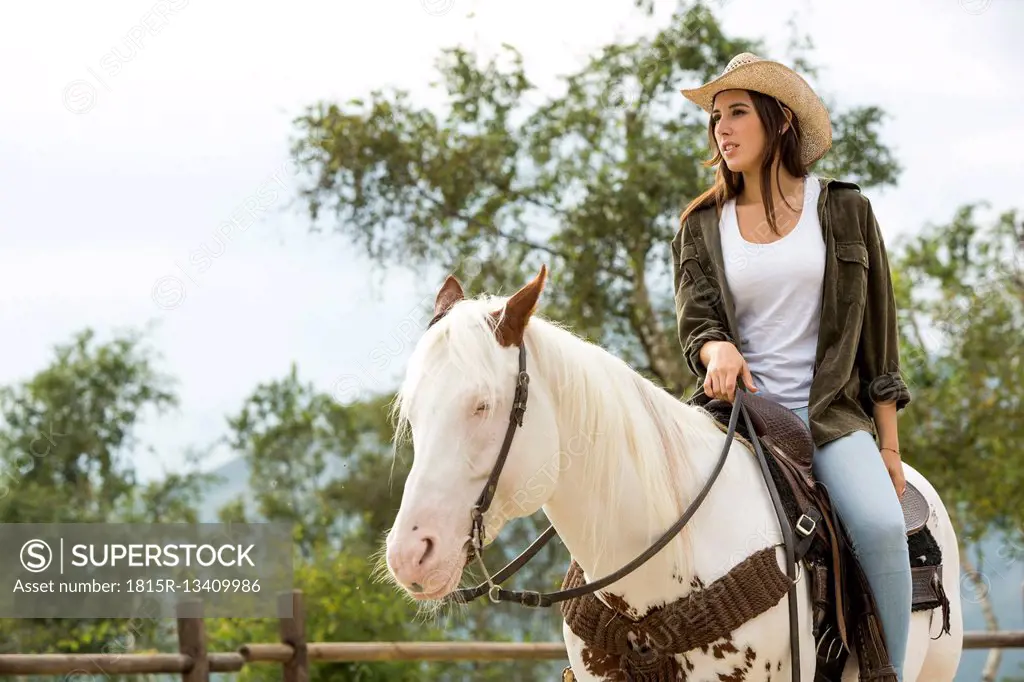 Young woman riding horse at riding stable