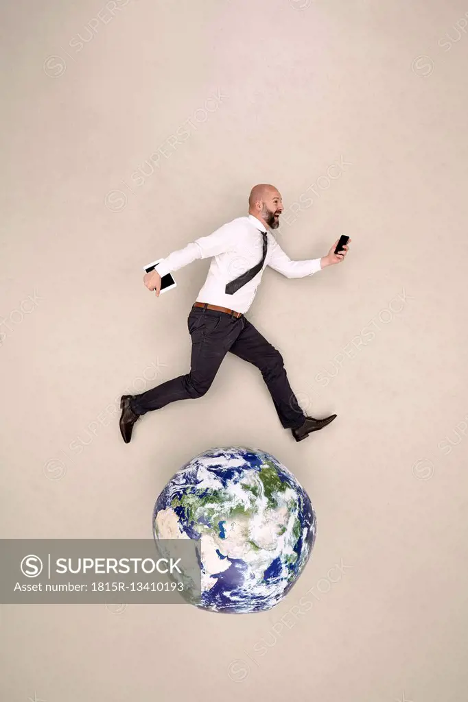 Businessman running on globe with mobile devices