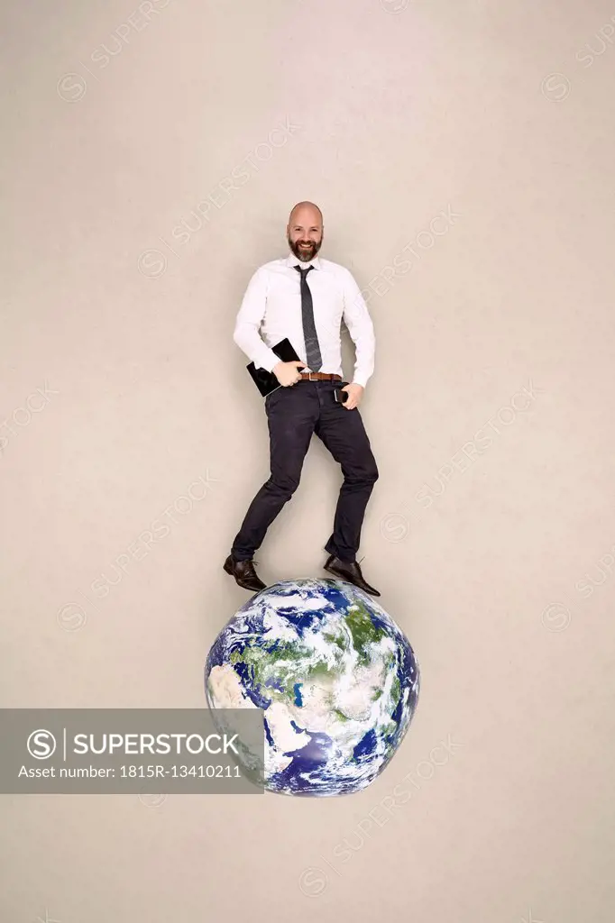 Businessman standing on globe with mobile devices