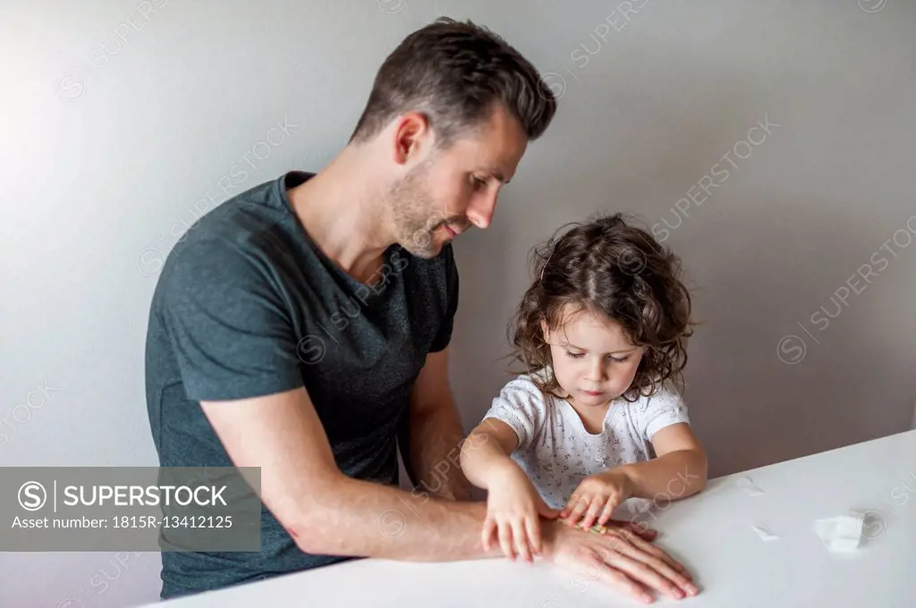 Daughter attaching plaster to father's hand