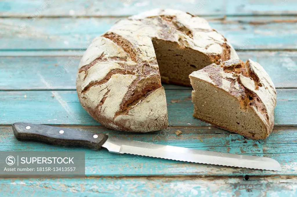Rustic rye bread on blue wood, knife