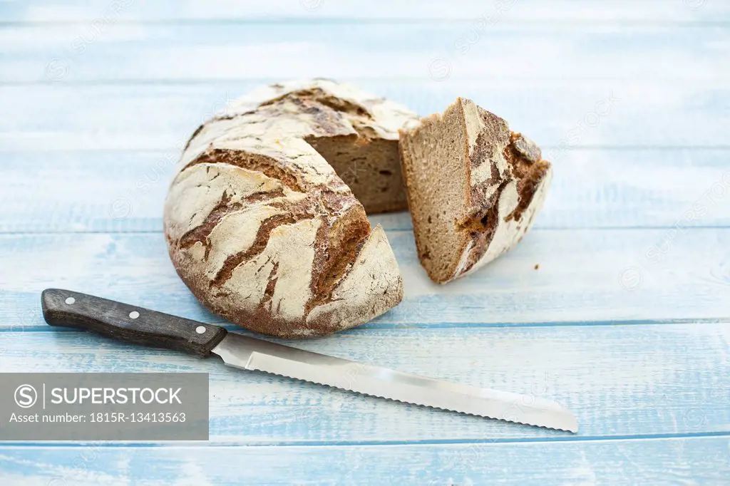 Rustic rye bread on blue wood, knife