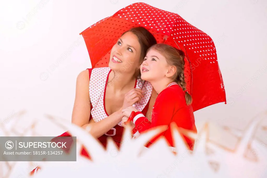 Mother and daughter under umbrella, smiling