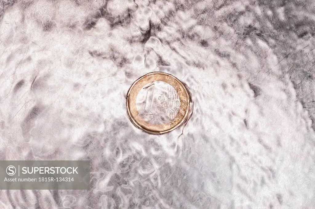 Euro coin in kitchen sink with flowing water, close up