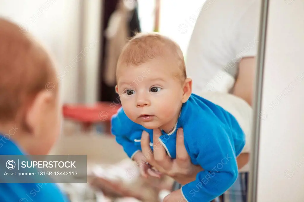 Baby being held to see his own reflection in mirror