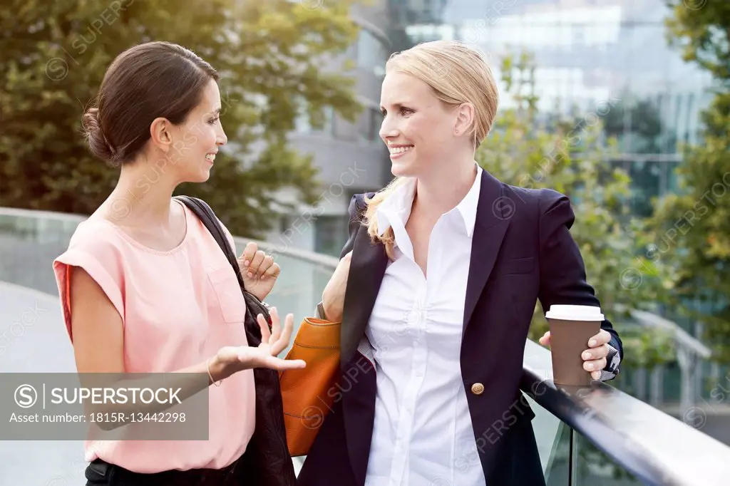 Two businesswomen talking outside during a coffee break
