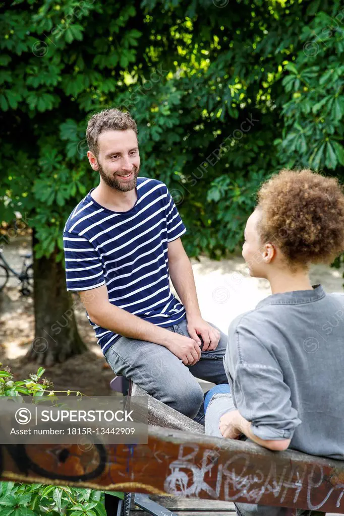 Young man smiling at woman in park