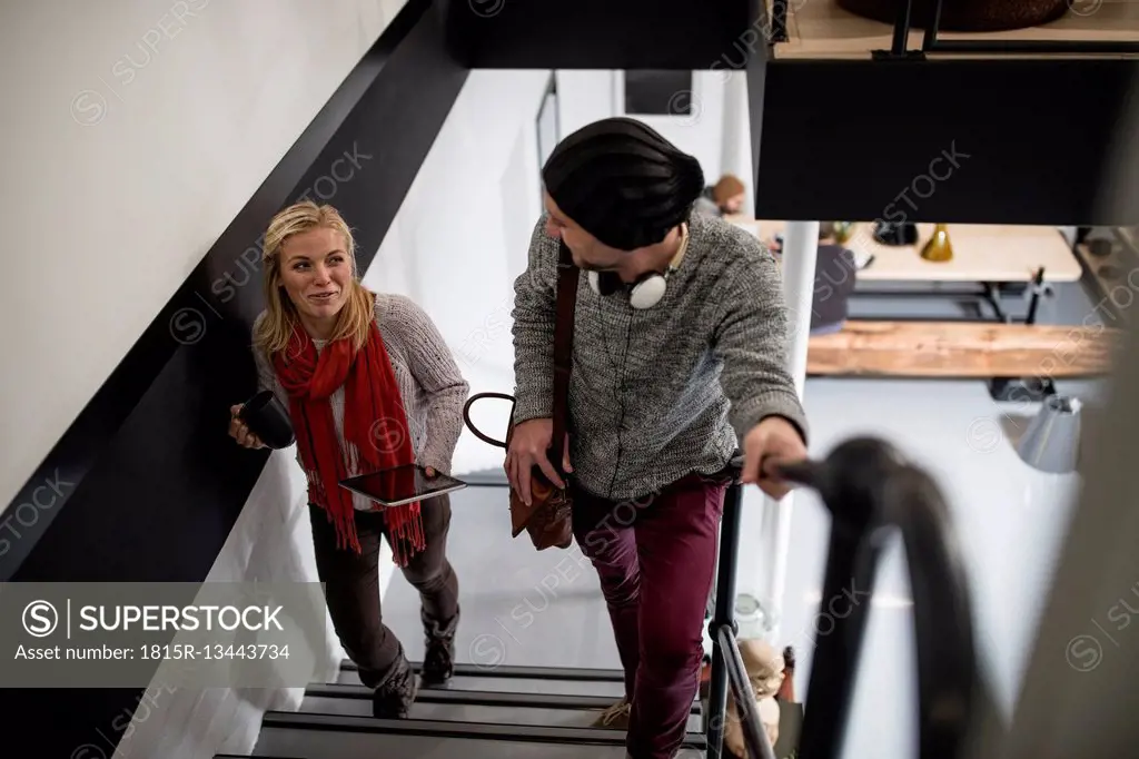 Young woman and man with headphones walking up stairs