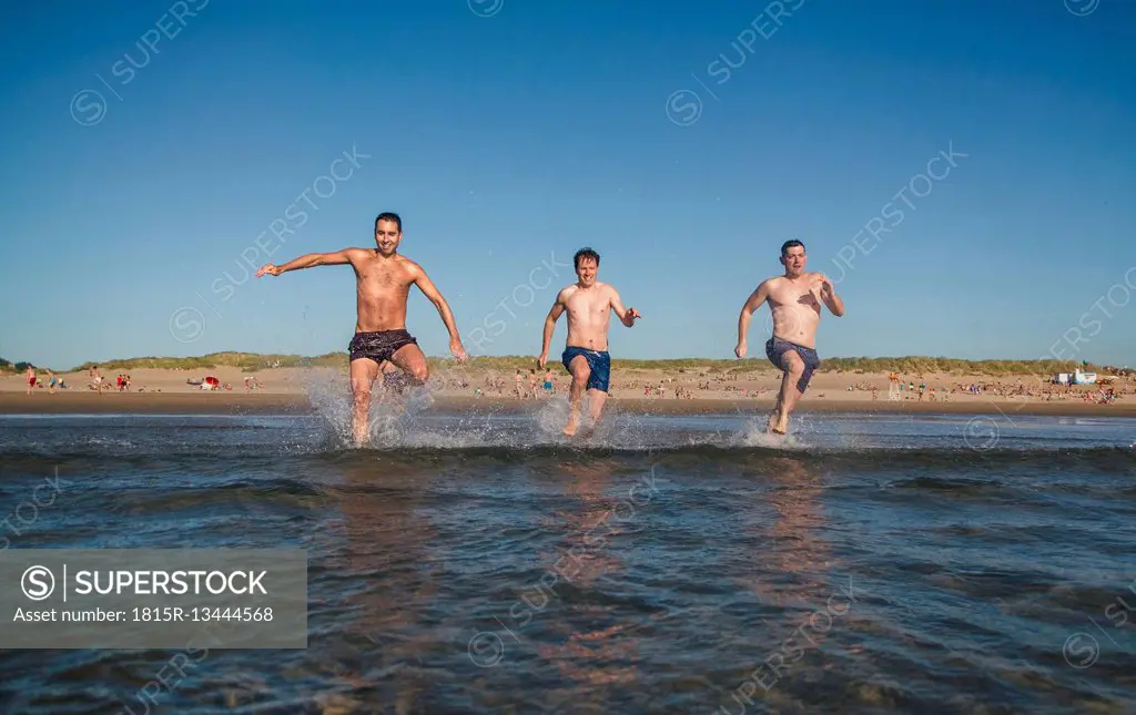 Friends running and jumping into the sea