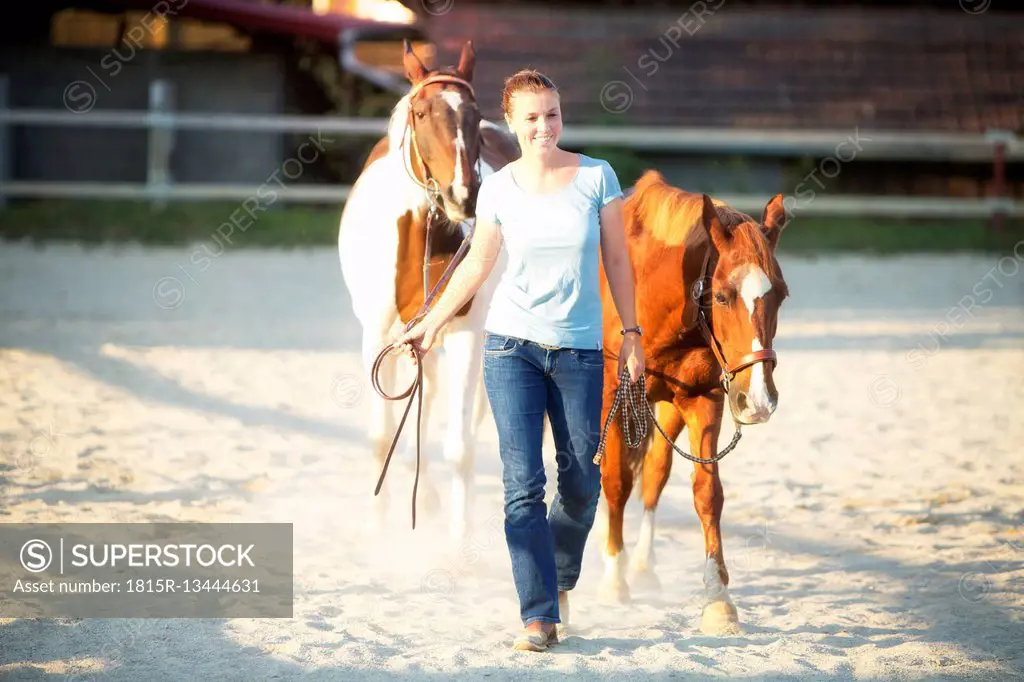 Young woman leading two horses