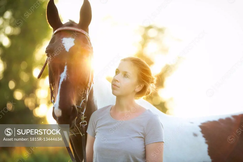 Young woman with horse at sunset