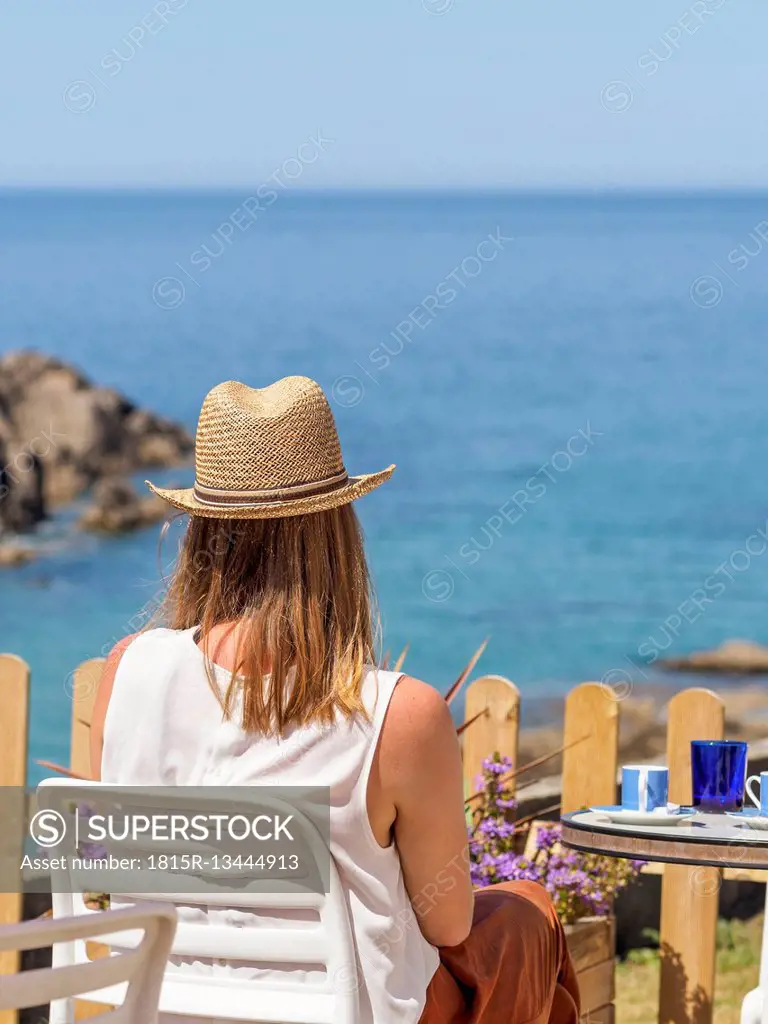 Woman sitting at the sea, drinking coffee