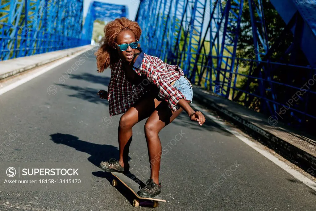 Young woman on skateboard on a bridge