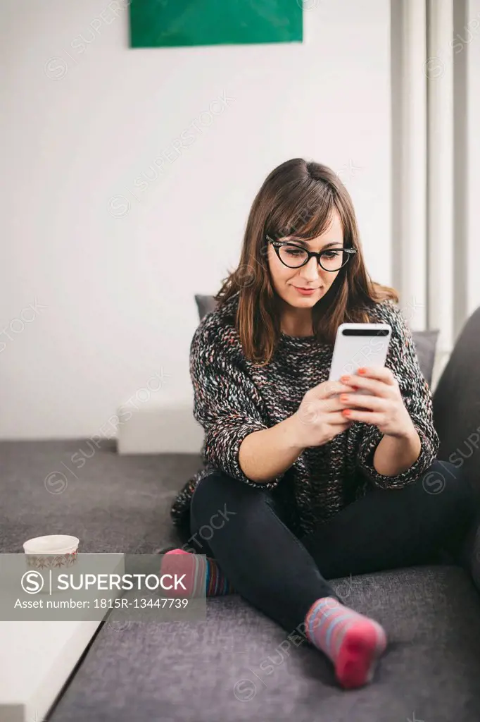 Young woman relaxing on the couch looking at her smartphone
