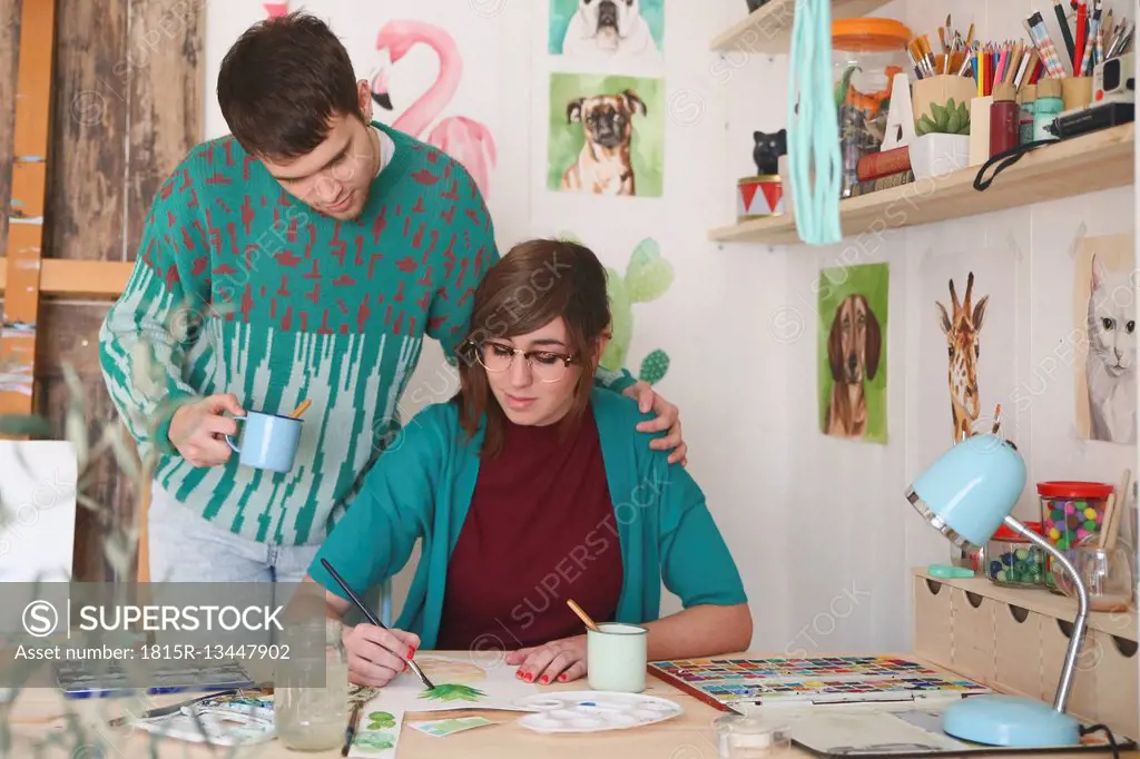 Artist painting in her studio while her boyfriend watching her