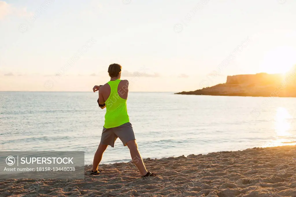 Spain, Mallorca, Jogger at the beach in the morning, stretching