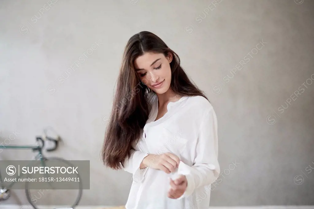 Young woman rolling up sleeve of her blouse