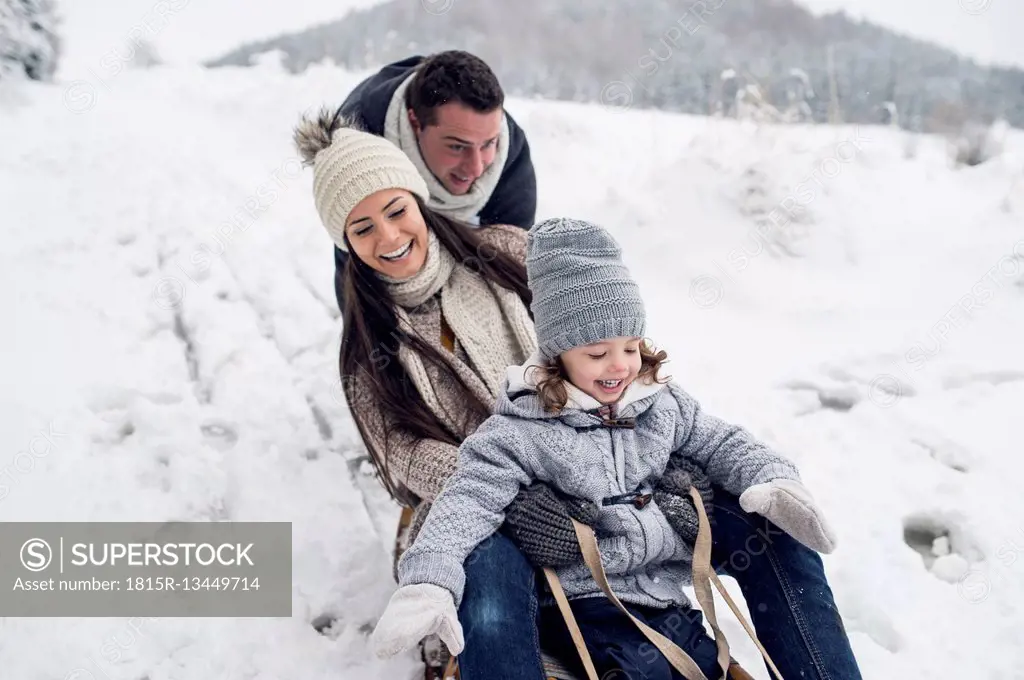 Happy family on sledge in winter landscape