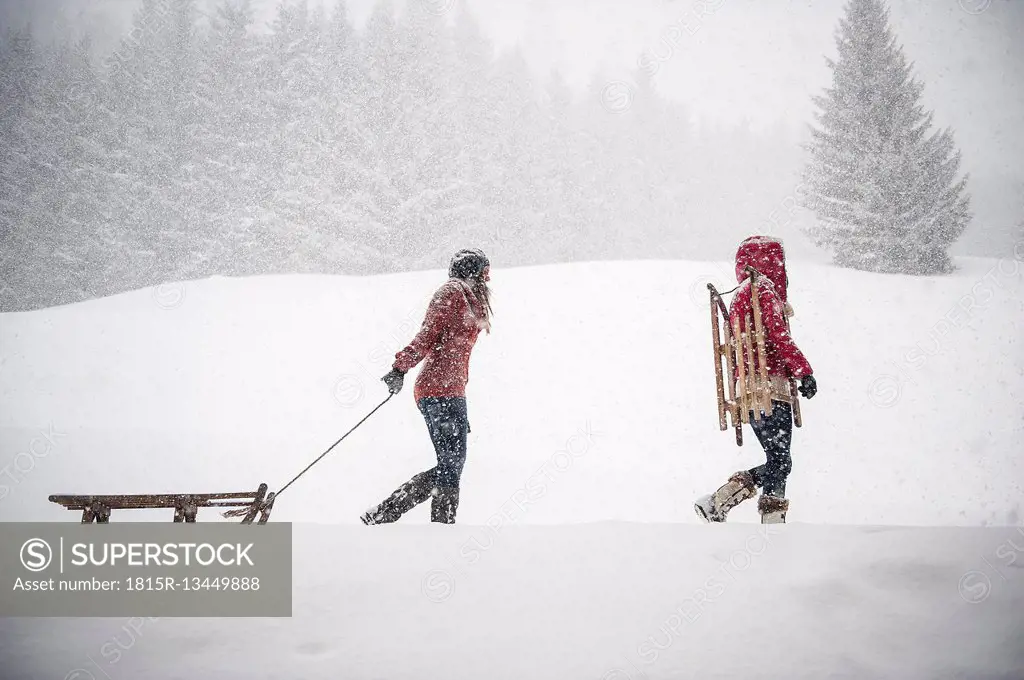 Two young women with sledges in heavy snowfall