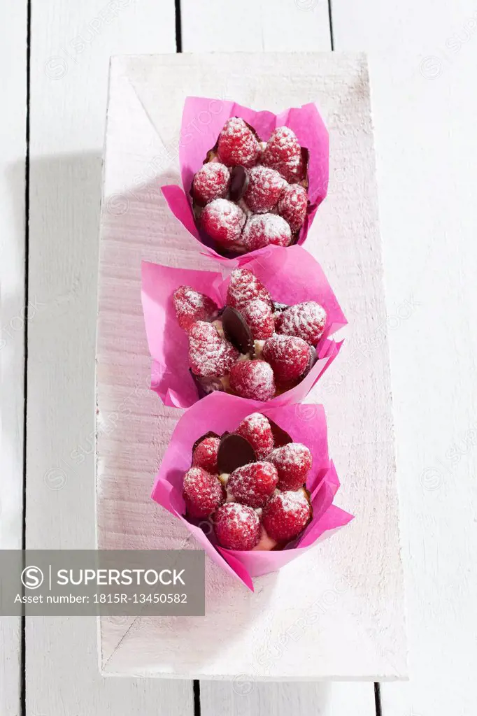 Three raspberry muffins in pink paper collars