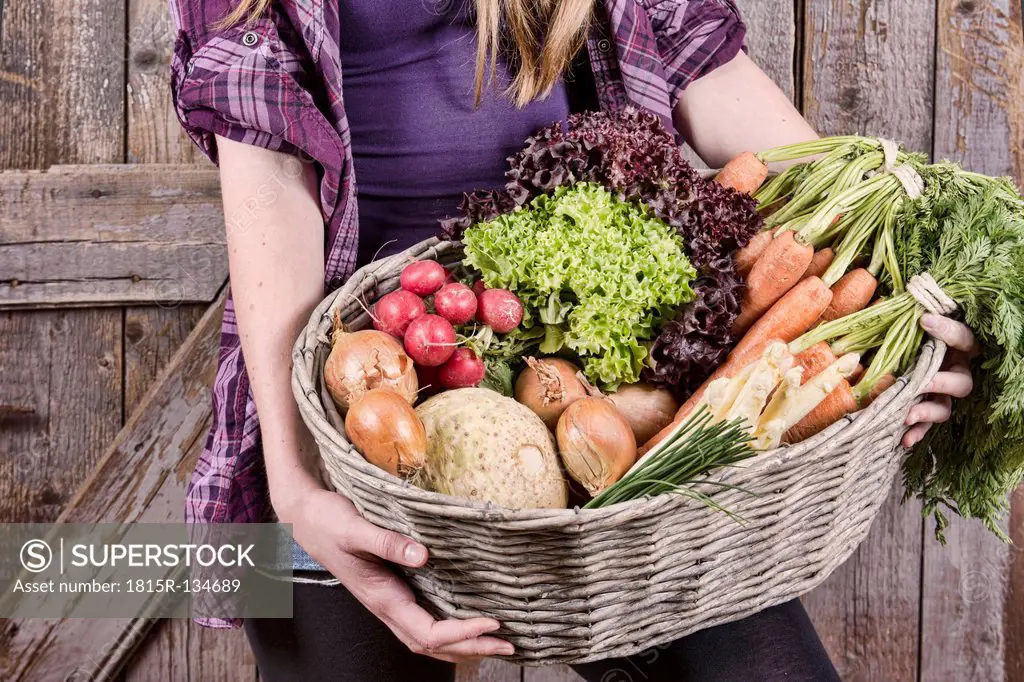 Germany, Teenage girl holding basket with organic vegetables