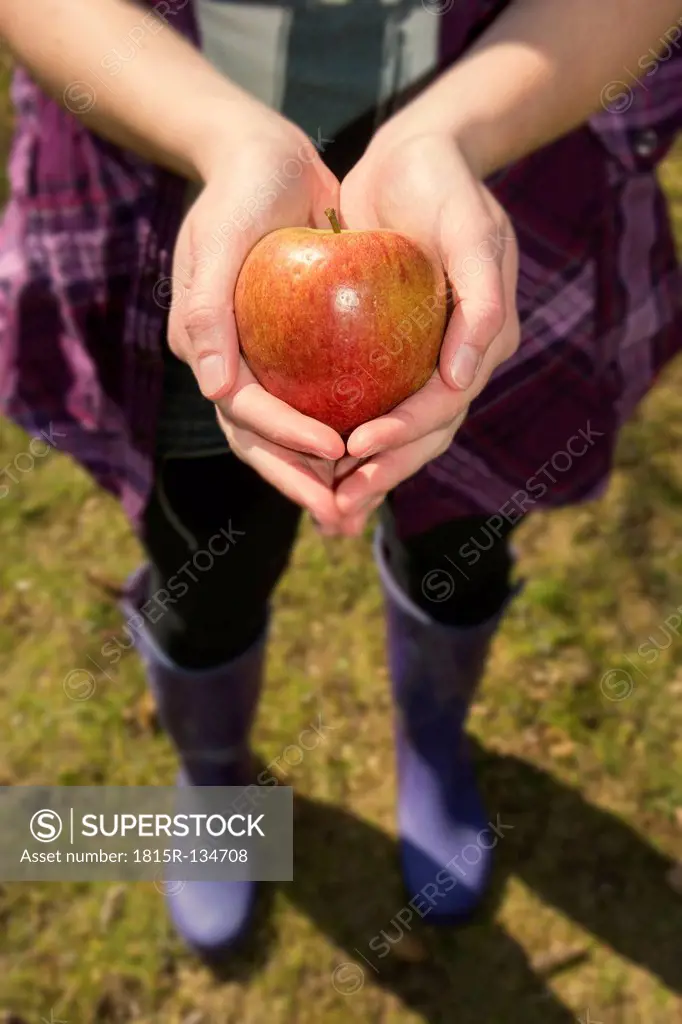 Germany, Teenage girl holding organic apple