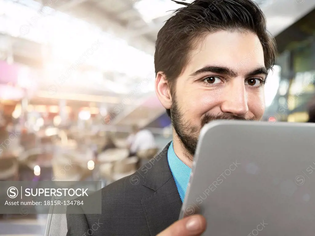 Portrait of young businessman using digital tablet, smiling