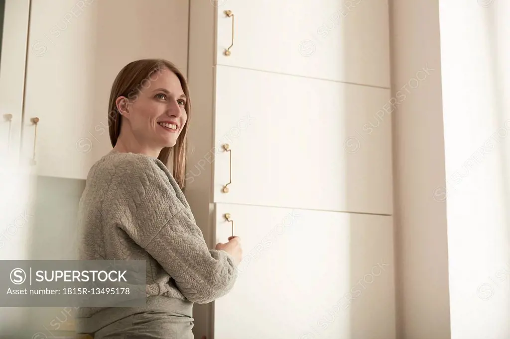 Smiling woman in kitchen at fridge