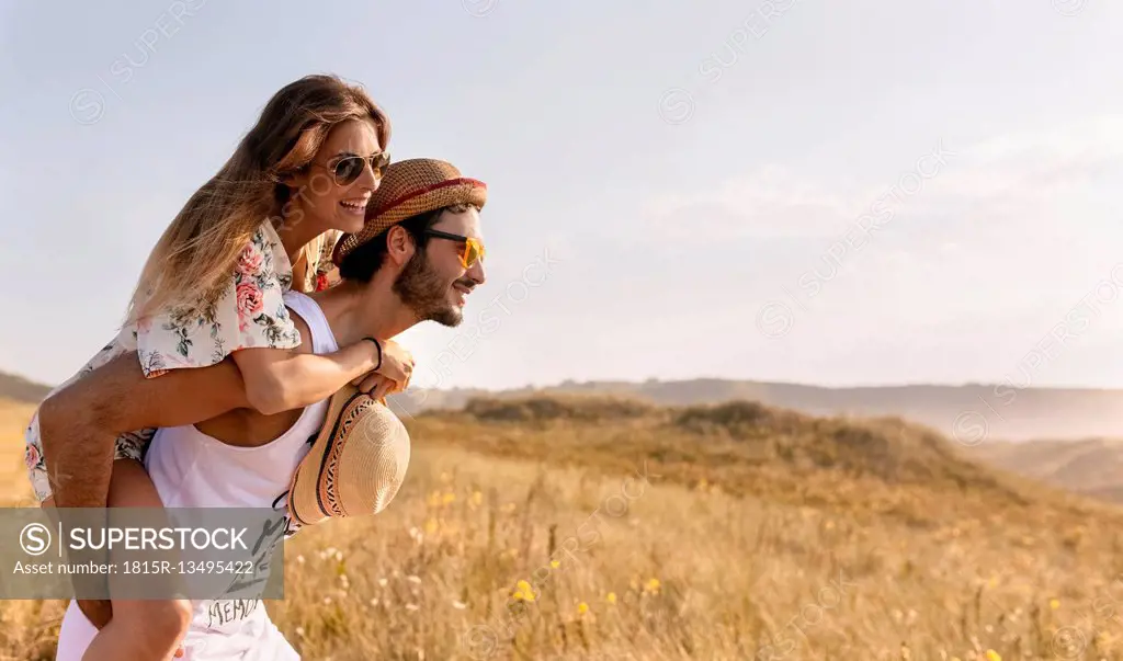 Man giving his girlfriend a piggyback ride in nature