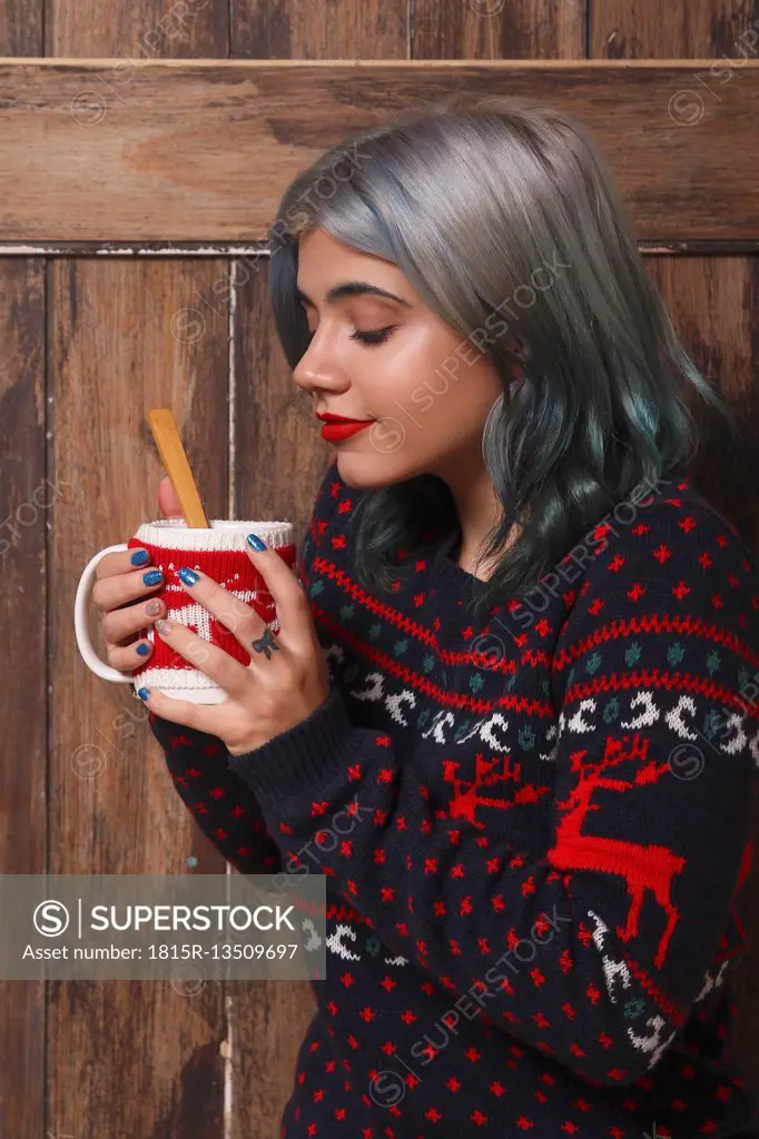Young woman enjoying a hot chocolate in front of wooden wall
