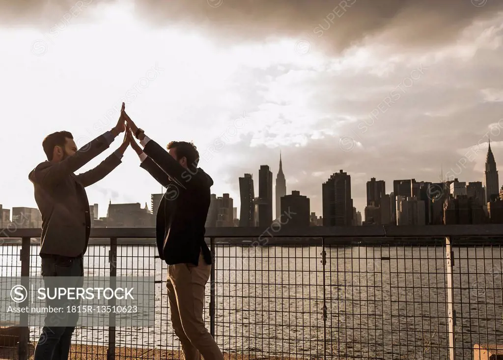 USA, New York City, two businessmen together at East River