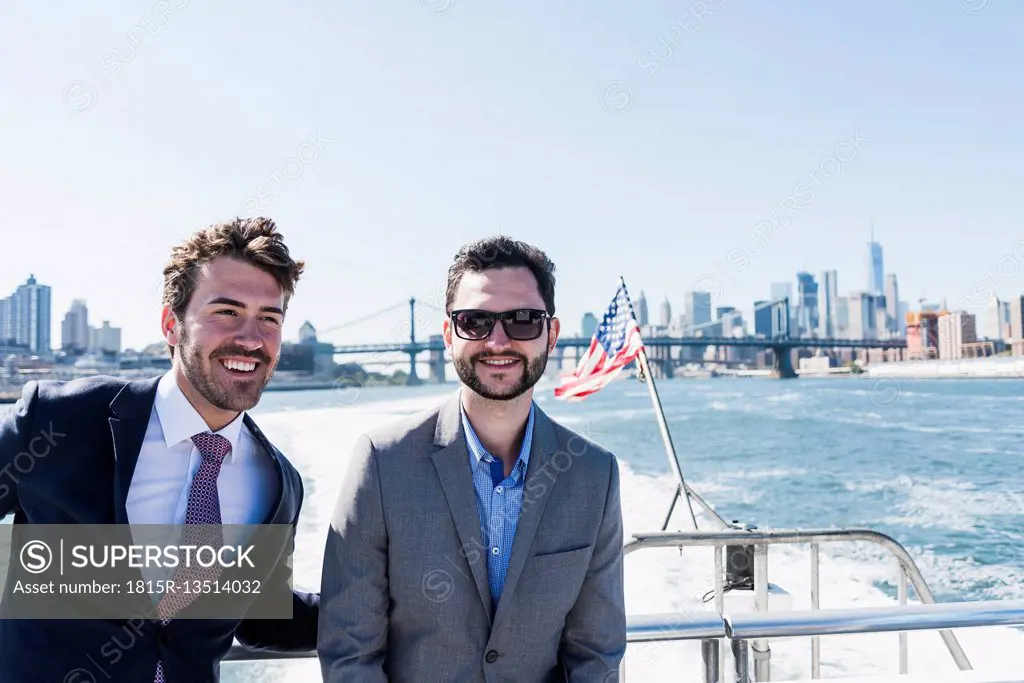 USA, New York City, two smiling businessmen on ferry on East River