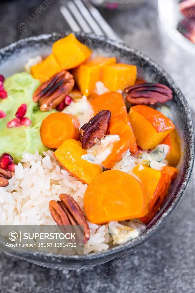 Bowl of autumnal salad with carrots, pumpkin, sweet potatoes, pecan, guacamole, pomegranate and rice