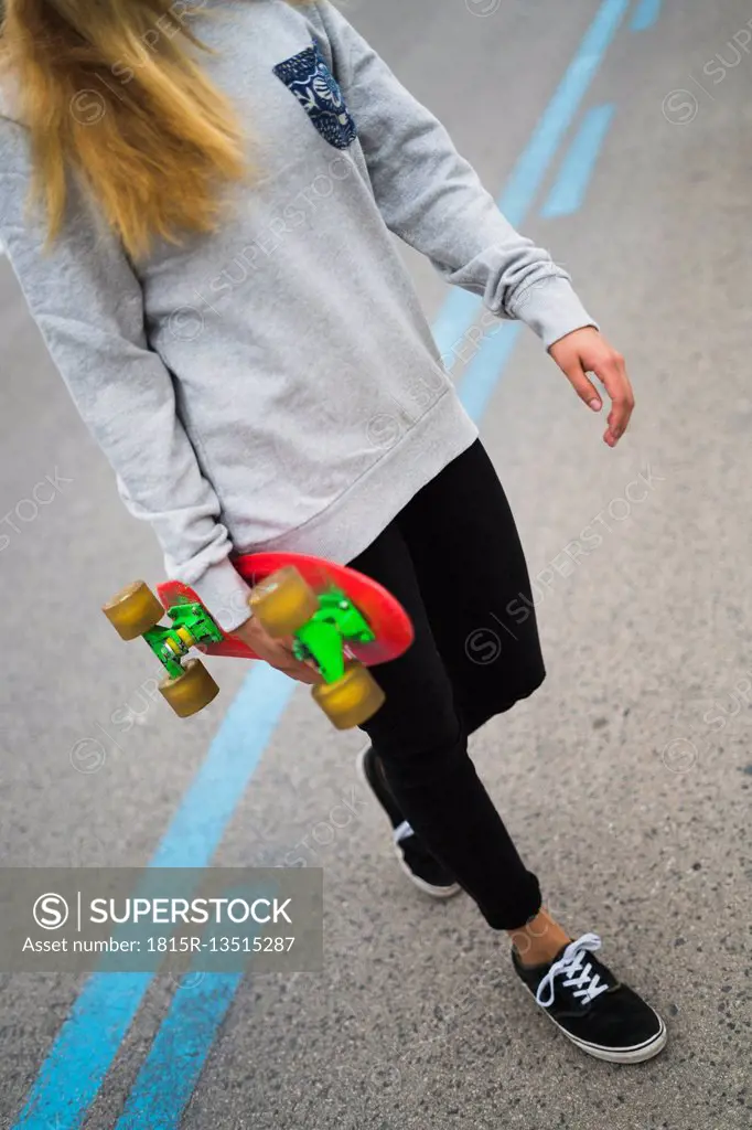 Young woman with skateboard crossing the street
