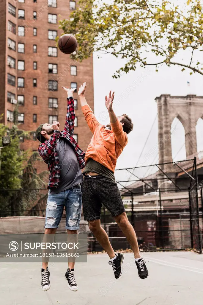 USA, New York, two young men playing basketball on an outdoor court