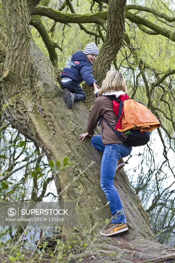 Germany, Kiel, Mother and son climbing on tree