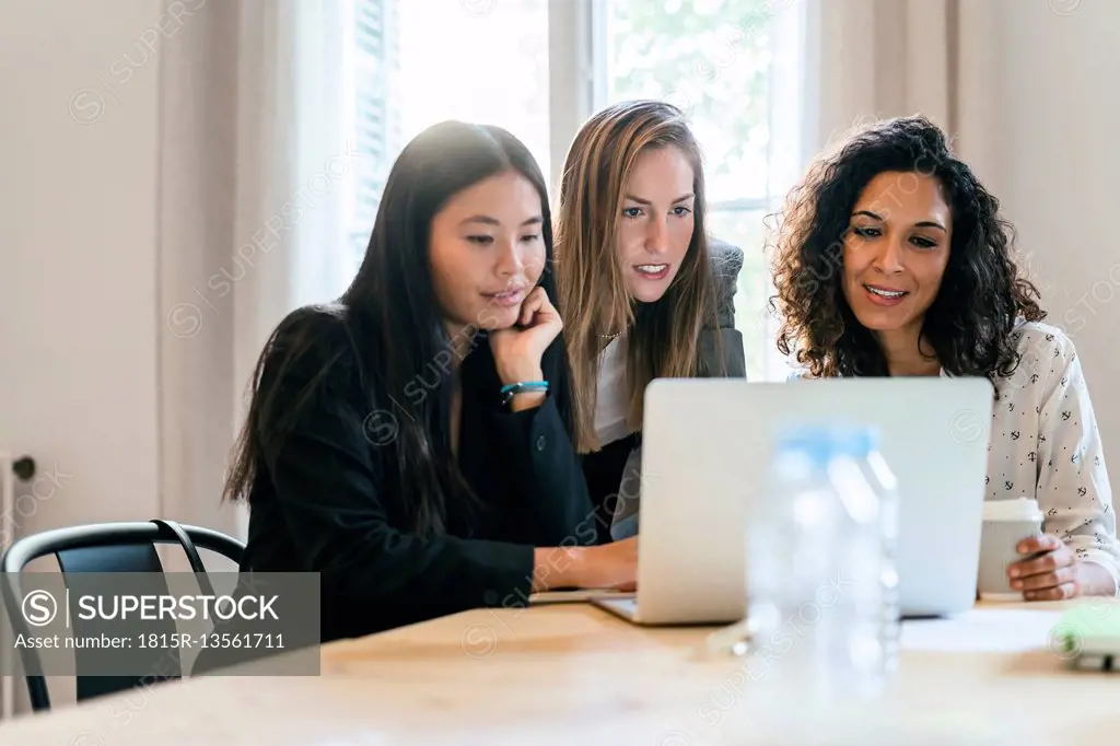 Three businesswomen working together on laptop