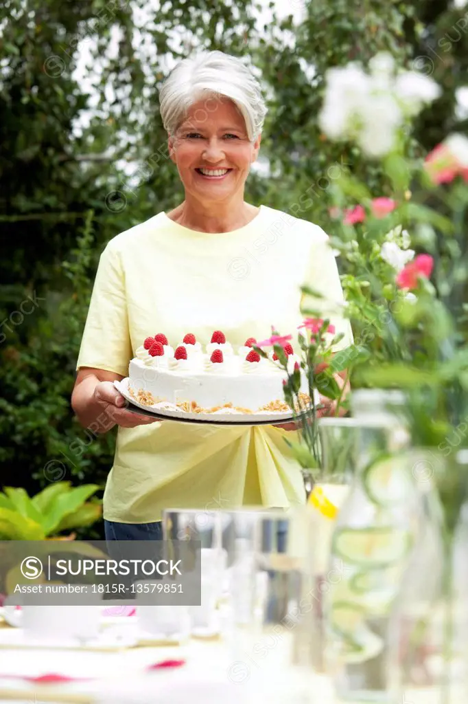 Mature woman serving cream cake in garden