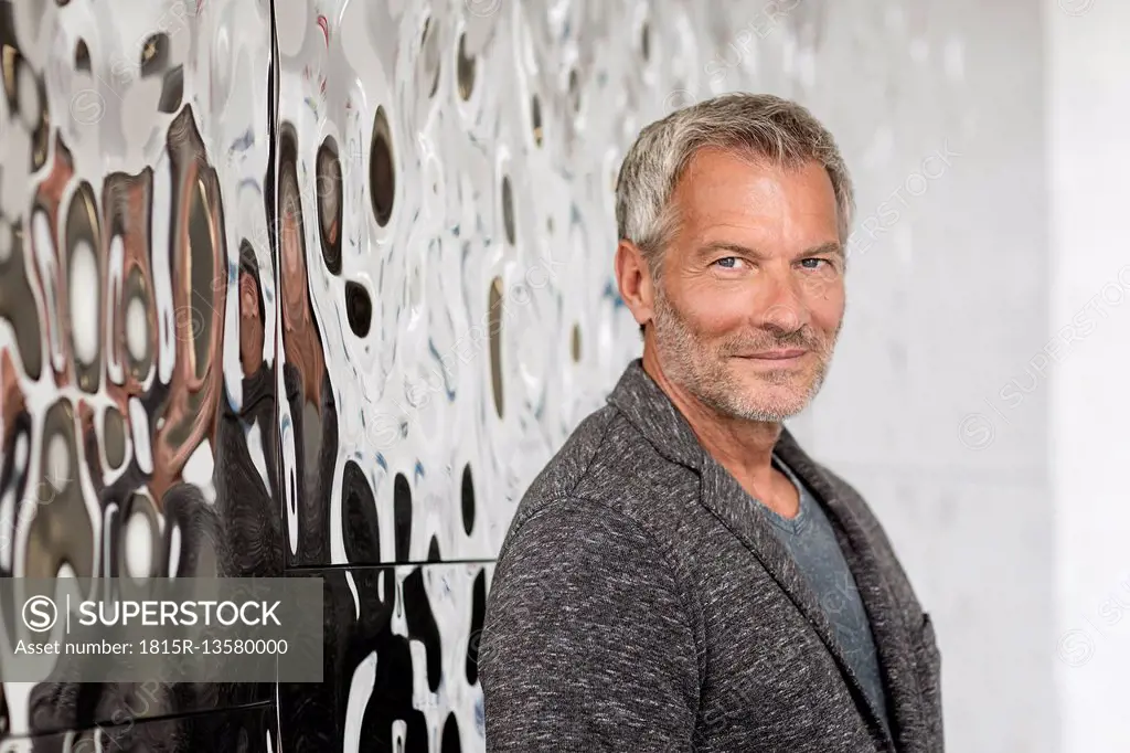 Portrait of confident mature businessman in front of rippled wall