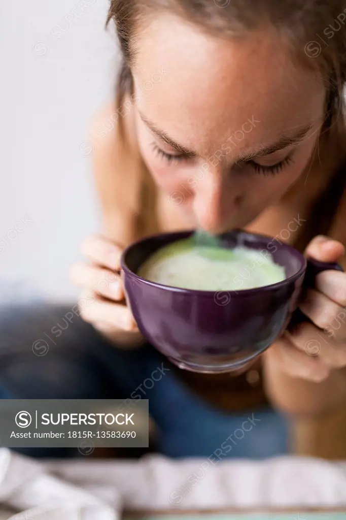 Woman drinking matcha latte at home